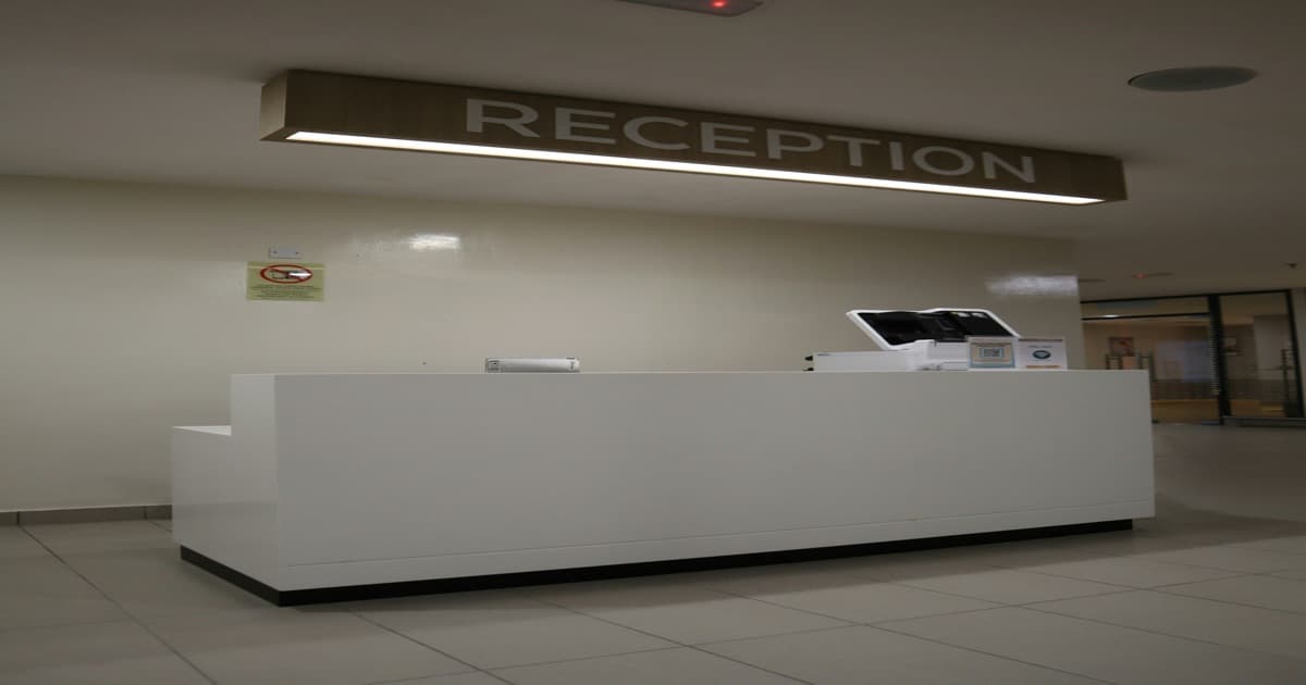 Recepção moderna com placa indicativa, evocando o setup tradicional de check-in que pesa na operação de aluguel de temporada