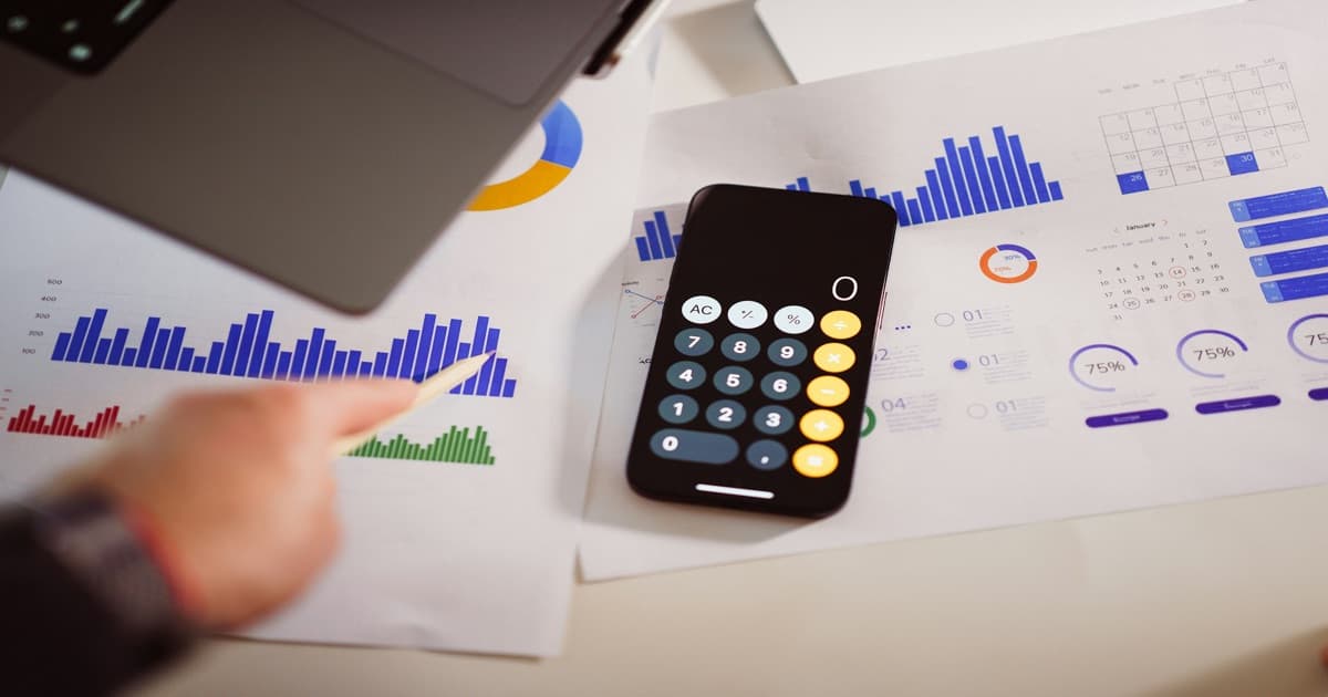 Calculadora ao lado de um laptop sobre uma mesa, evocando análise de custos e ROI da operação de aluguel de temporada