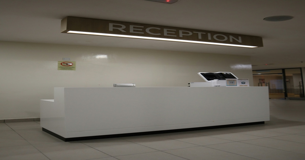 Recepção moderna com placa indicativa, evocando o setup tradicional de check-in que pesa na operação de aluguel de temporada